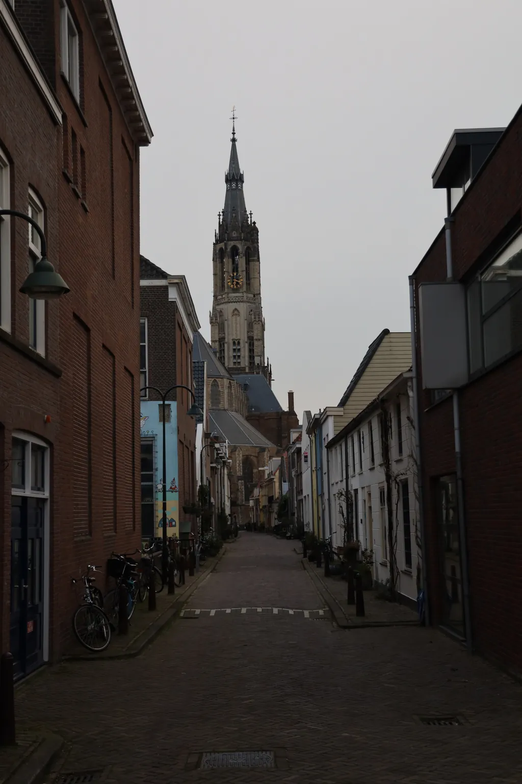 A narrow street of old houses with a church tower at the end